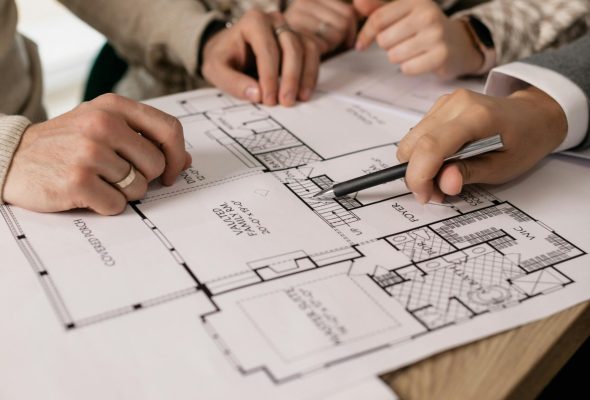 People discuss architectural plans in a real estate planning session, highlighting teamwork.