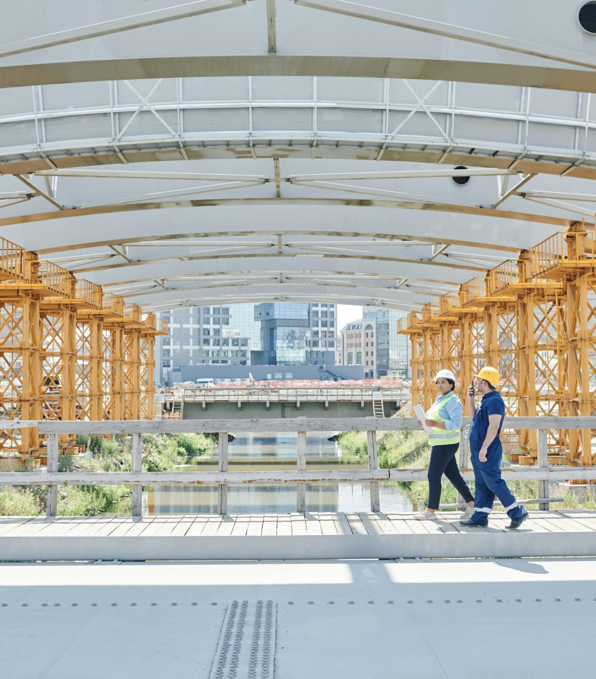 Two construction workers with hardhats inspecting a bridge construction site, emphasizing safety.