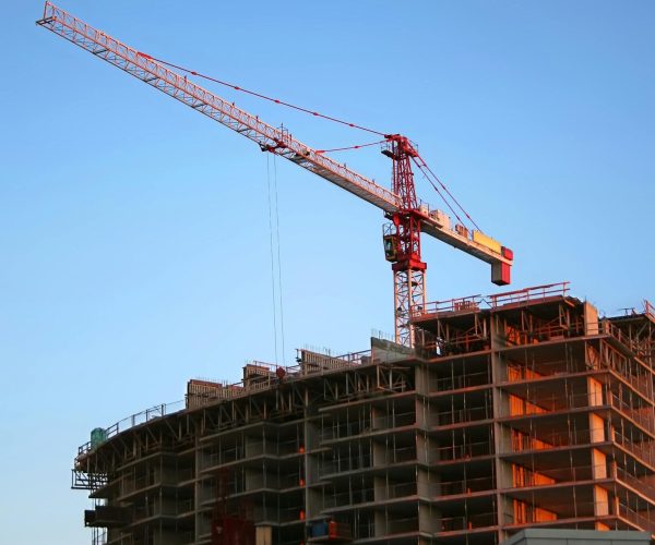 Tower crane on a high-rise building under construction at sunset, showcasing modern urban development.